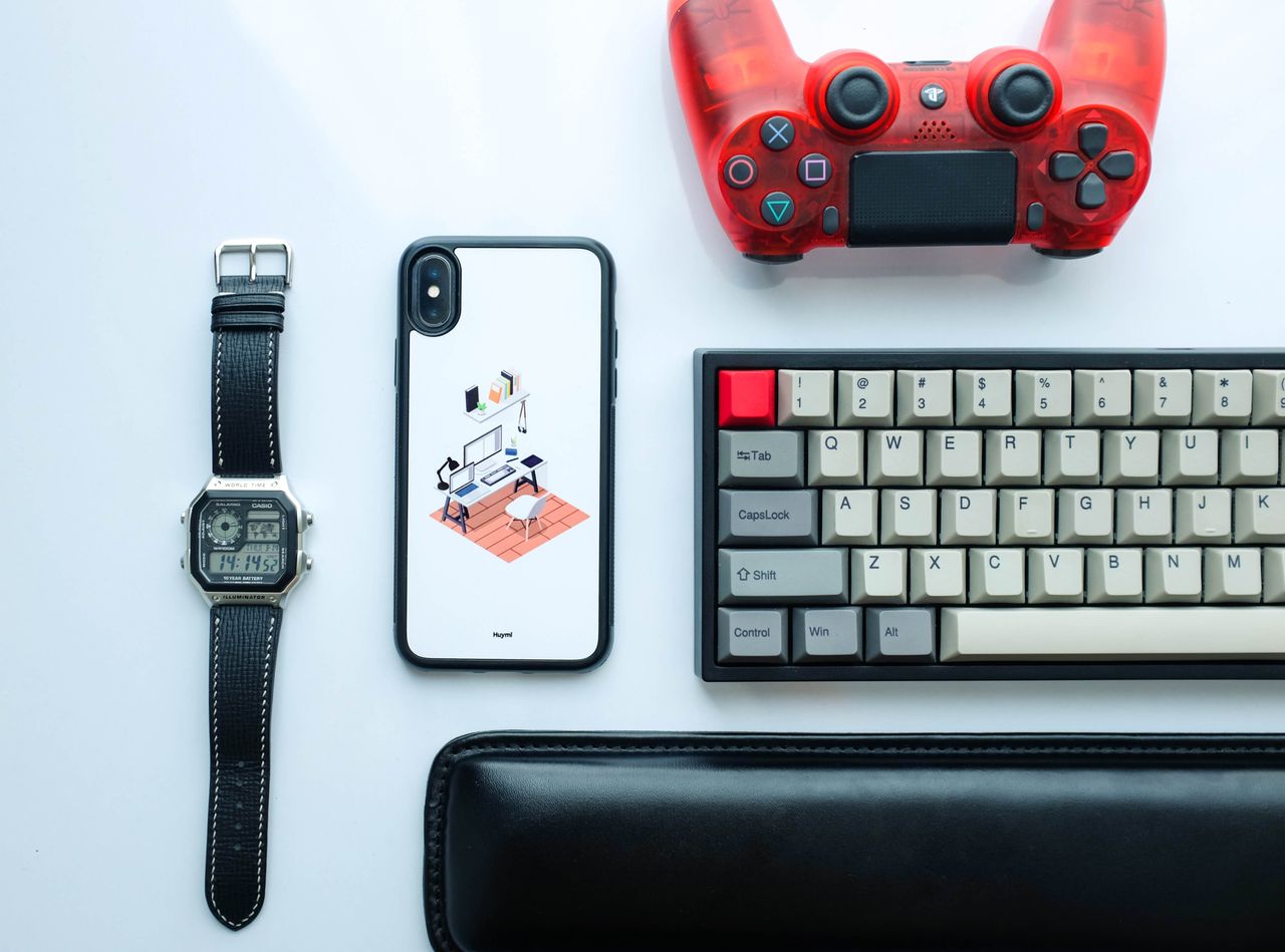 our-experience Top view of modern gadgets including a smartphone, watch, game controller, and keyboard.