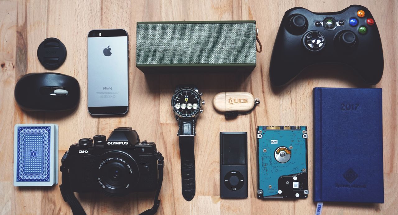 about-02 Flat lay of various modern gadgets, accessories, and tech items on wooden surface.